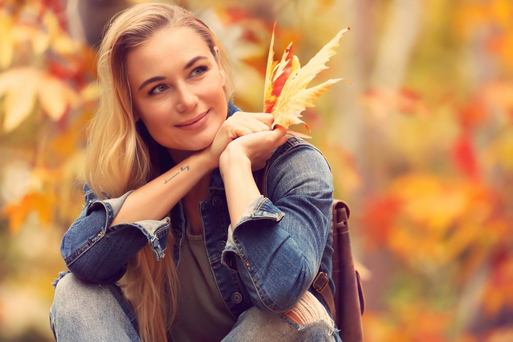A woman with beautiful skin sitting in the park in the fallPicture